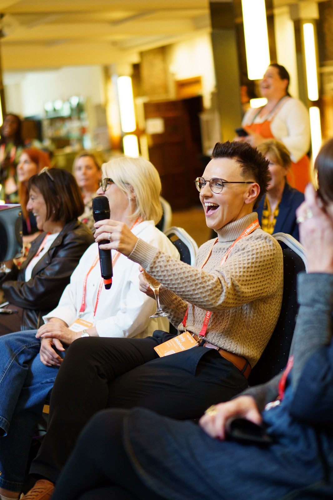 An attendee at a Workgroup HR event speaking into a microphone from the audience, laughing
